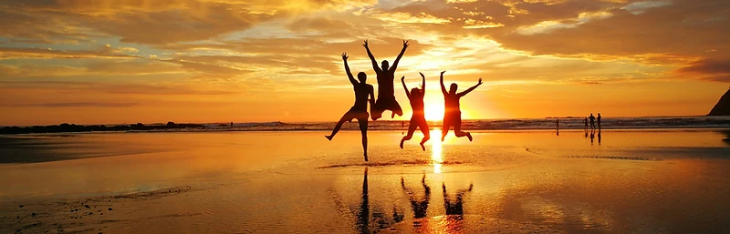 Friends jumping on the beach at sunset