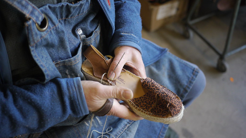 Artisan cousant une espadrille à la main dans son atelier basque
