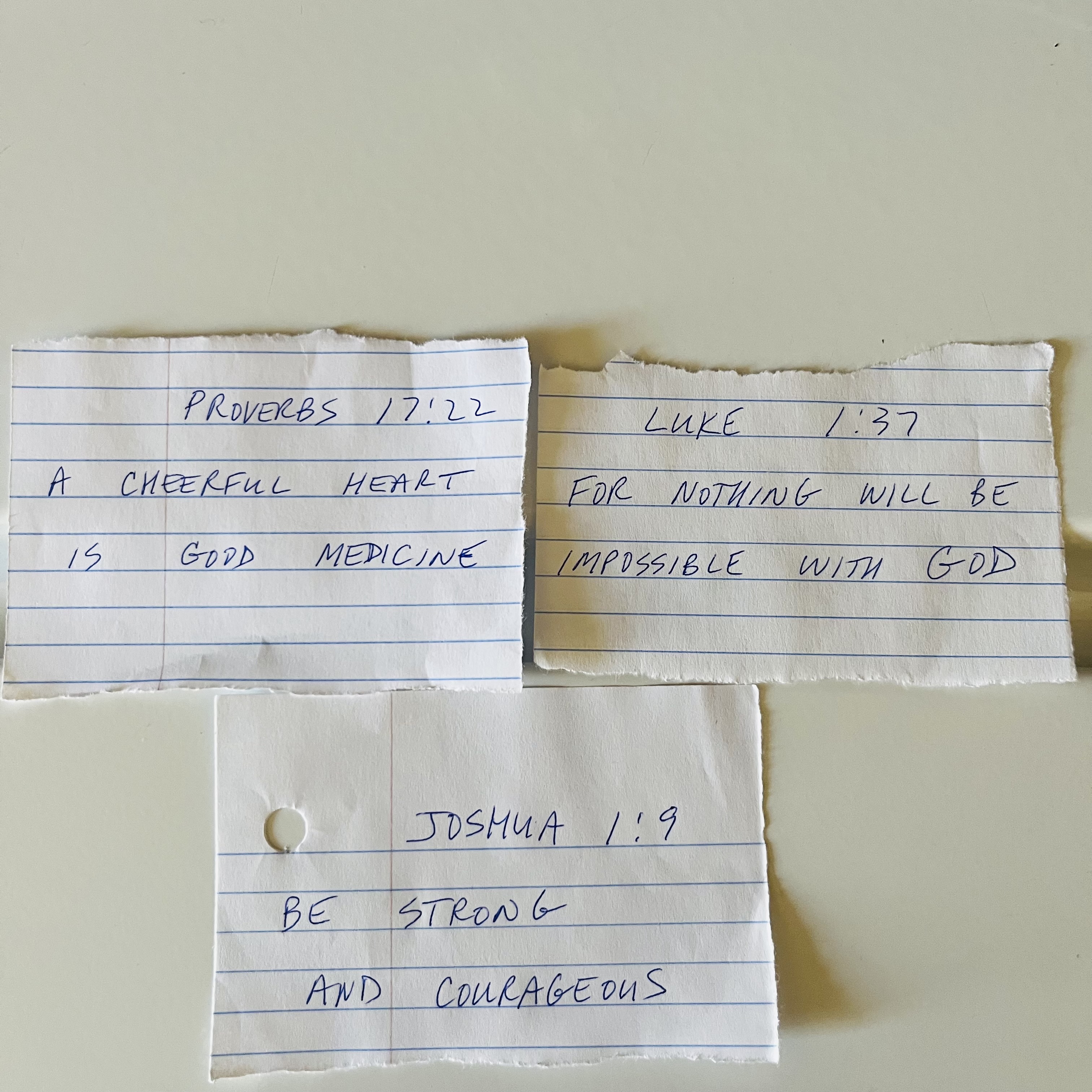 Handwritten Bible verses on torn pieces of lined notebook paper