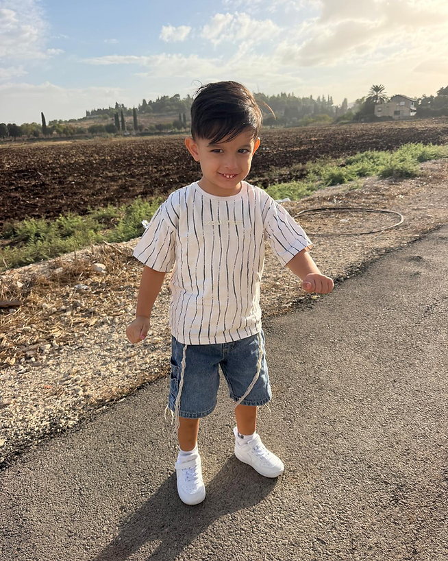 ילד מחייך עומד על דרך כפרית באור אחר הצהריים