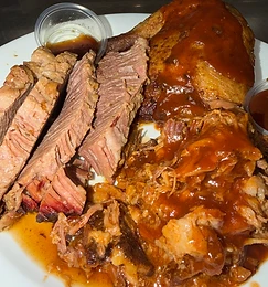 Sliced brisket and pulled pork plated with house BBQ sauce