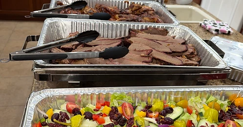 Catering spread with garden salad, sliced brisket, and house sides