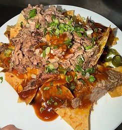 BBQ nachos topped with pulled pork, green onions, and jalapeños
