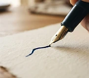 A hand writing a letter with a fountain pen