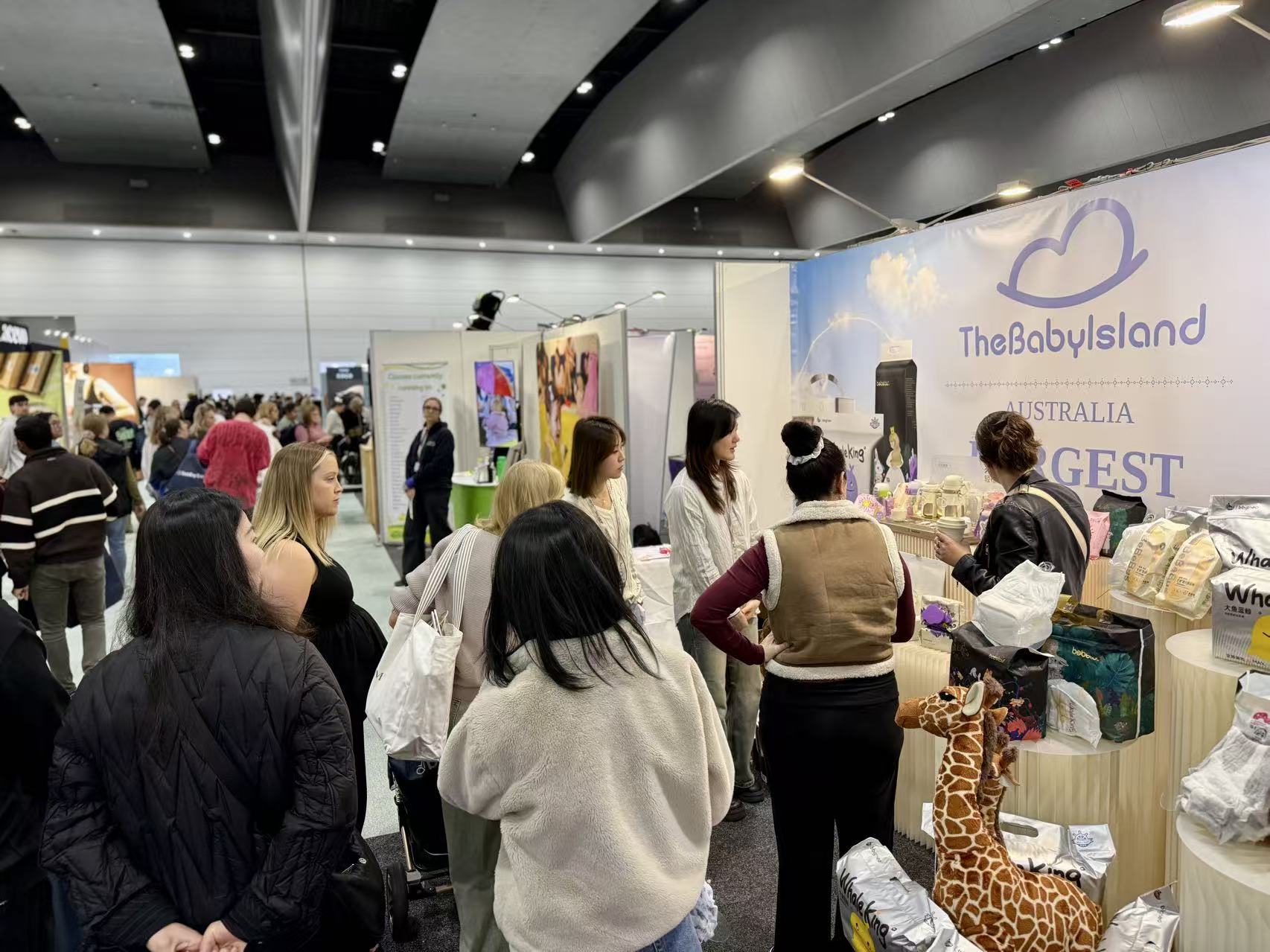 Attendees browsing the TheBabyIsland booth at a trade show