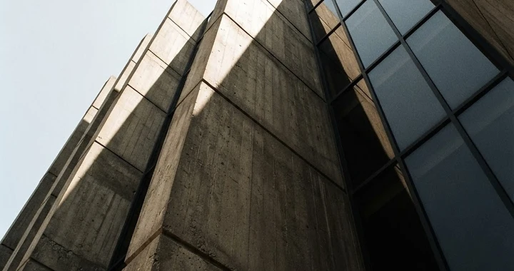 Low-angle view of a concrete and glass structure meeting the sky