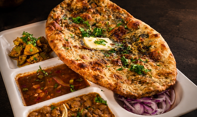 Amritsari Kulcha topped with melting butter and fresh herbs, served with chole and pickles