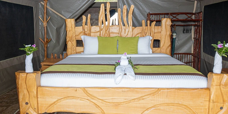 Kivuko safari tent interior with rustic wooden bed