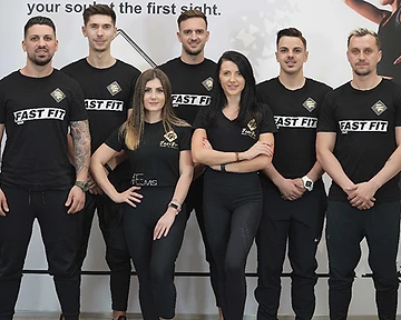 Six-member Fast Fit team in branded black uniforms posing against a studio wall in Riyadh