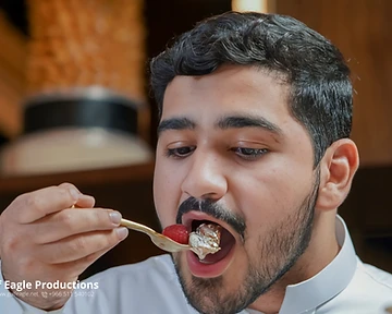 Guest in a white thobe tasting a dessert at a hospitality event in Riyadh