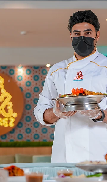 Chef presenting a plated dish in a Riyadh restaurant kitchen