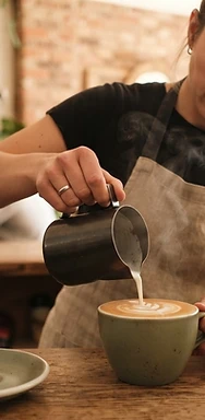 Barista pouring latte art into a ceramic cup