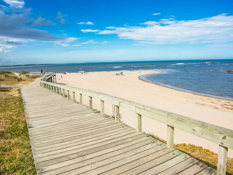 Wooden boardwalk curving toward the Punta del Este shoreline