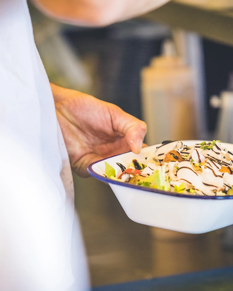 Salade fraîche dressée dans une assiette émaillée à La Buvette des Bains