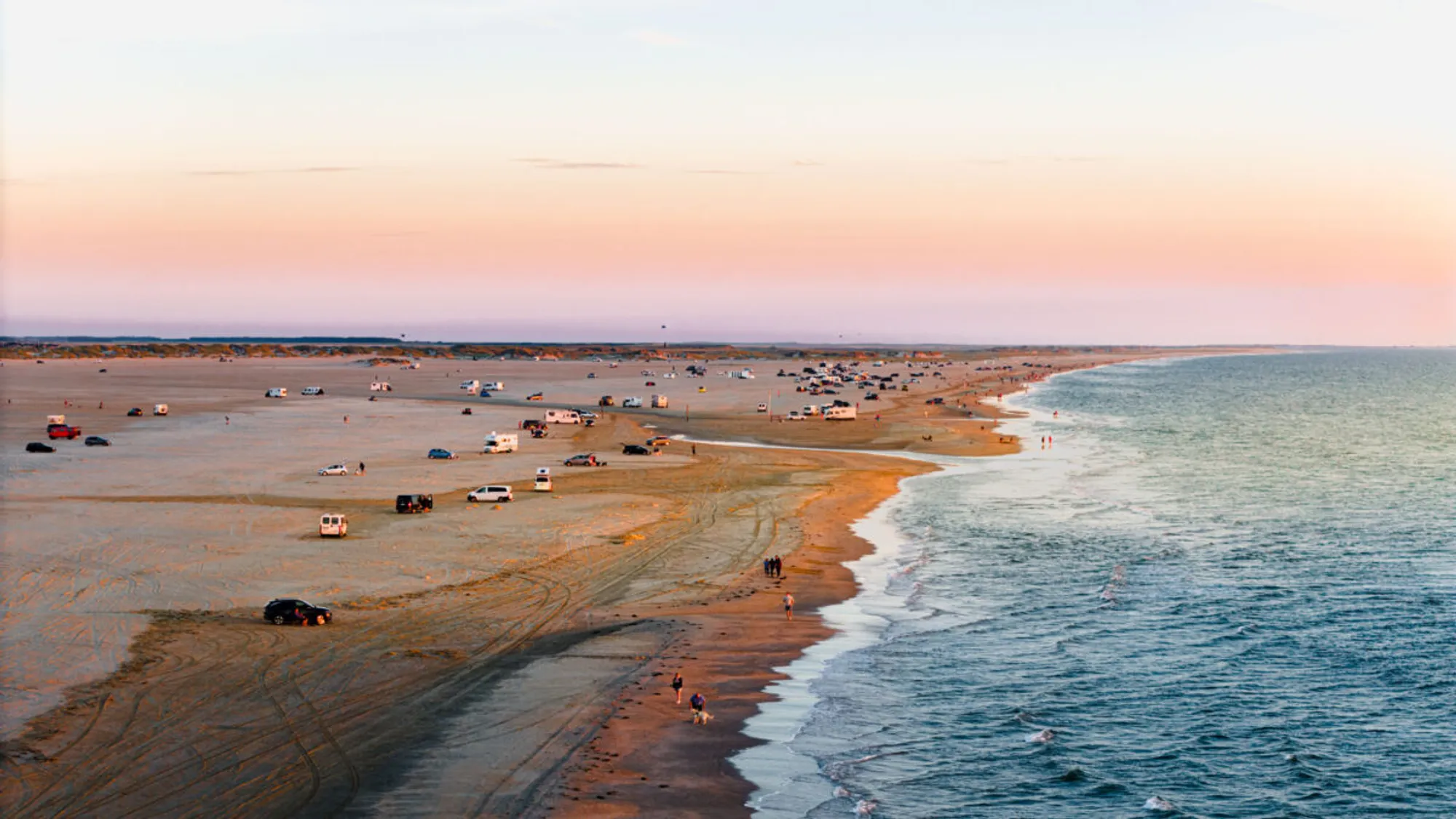 Lakolk Strand ved solnedgang med parkerede biler langs vandkanten
