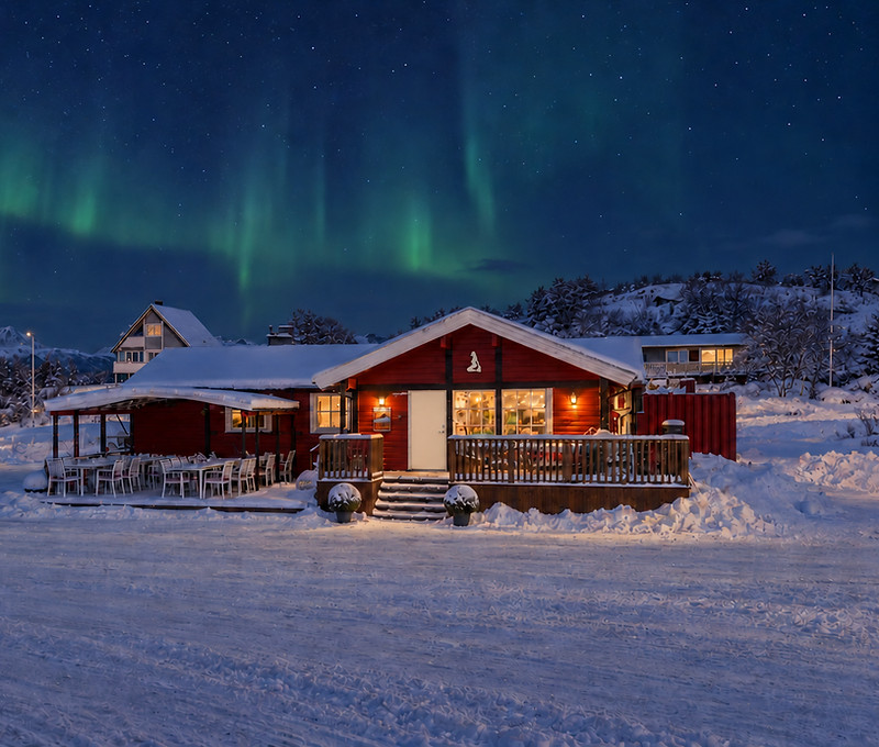 Havfrua Kro i vinterlandskap med snø, varm belysning, fjell og nordlys