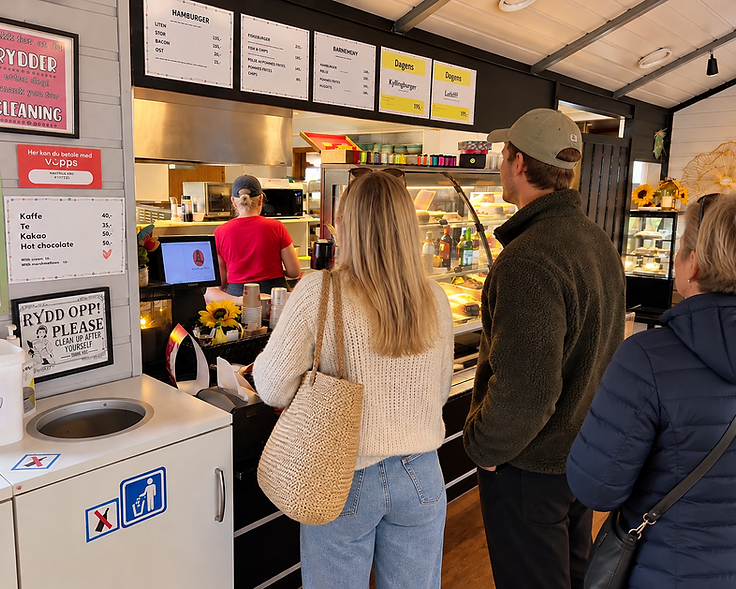 Interiør fra Havfrua Kro med gjester ved disken