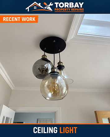 Three smoked-glass pendant shades suspended from a black ceiling plate beside a roof window.