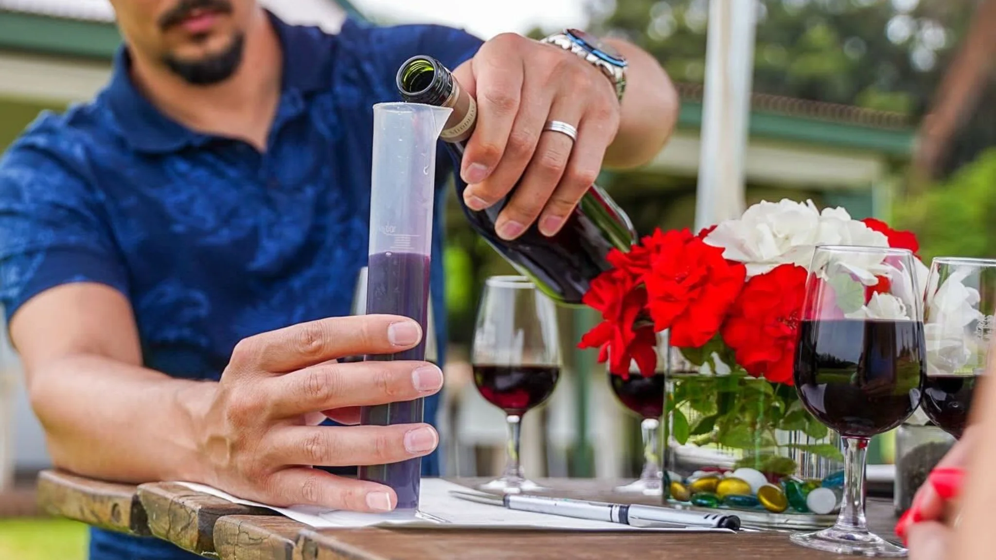 A visitor pouring red wine into a plastic measuring cylinder during the interactive Middelvlei Wine Blending Experience in Stellenbosch.