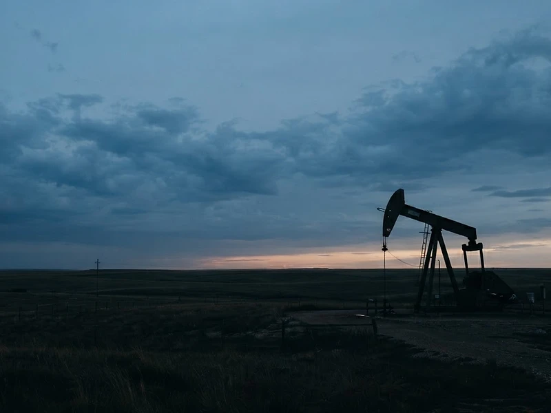 Kansas prairie at dusk under a subtle blue sky with a silhouetted pump-jack