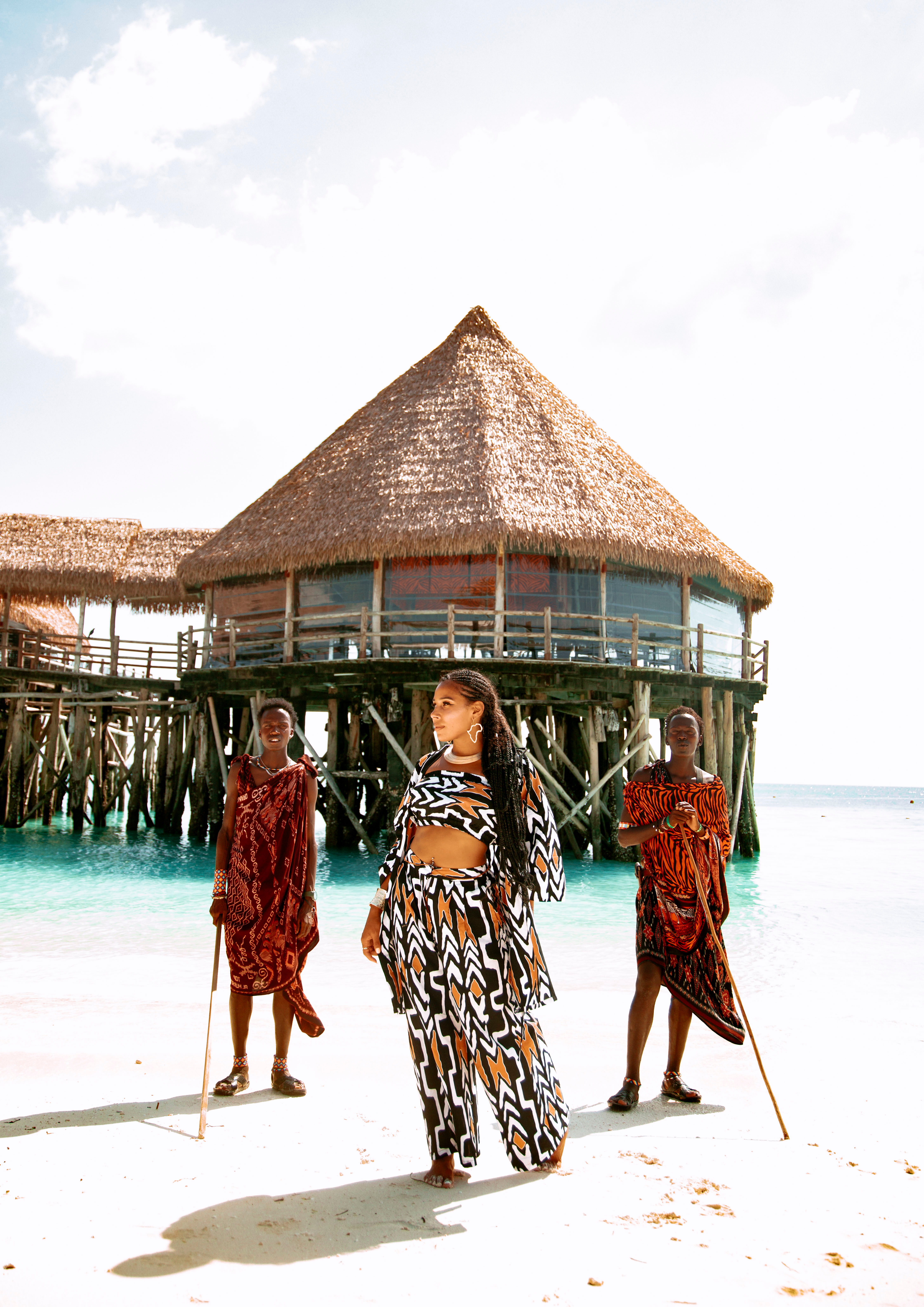 Taliya on a white sand beach with two Maasai men