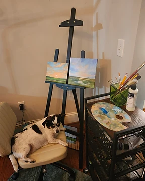 Julia Hughes' painting nook with an easel, canvas boards, and brushes