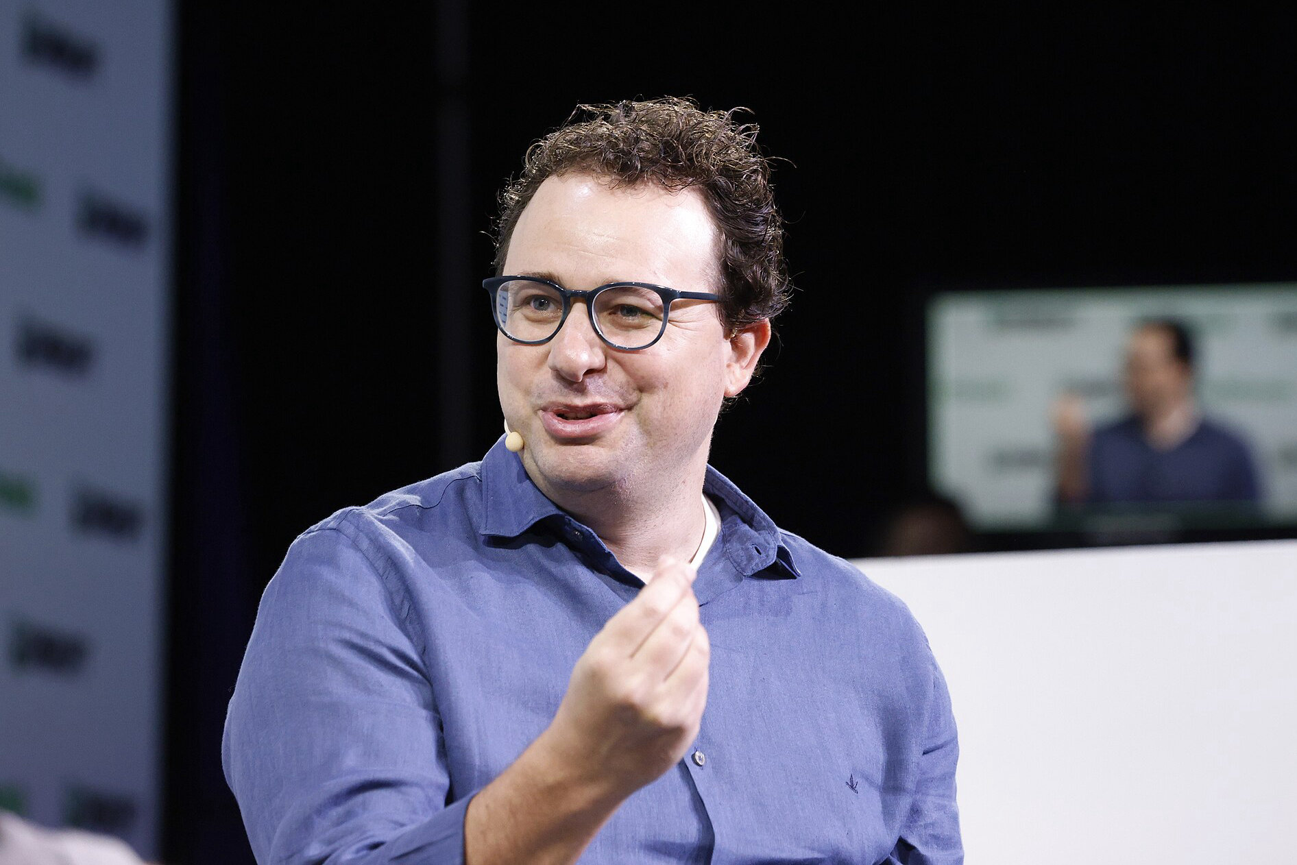 Dario Amodei, szef Anthropic, w okularach i niebieskiej koszuli, mówi podczas panelu na konferencji TechCrunch Disrupt 2023