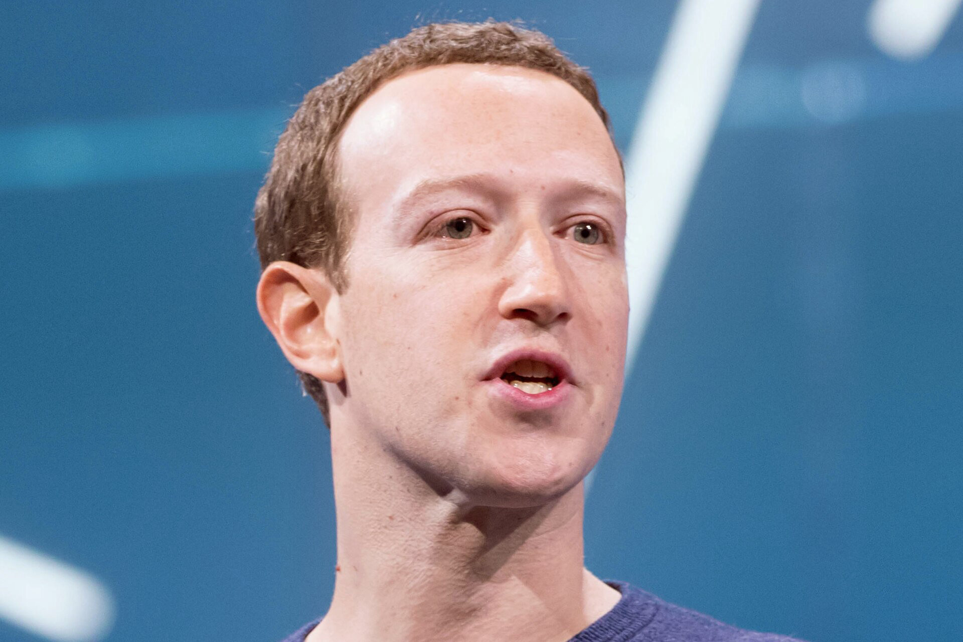 Mark Zuckerberg w niebieskim swetrze przemawia na scenie podczas konferencji F8 w 2018 roku