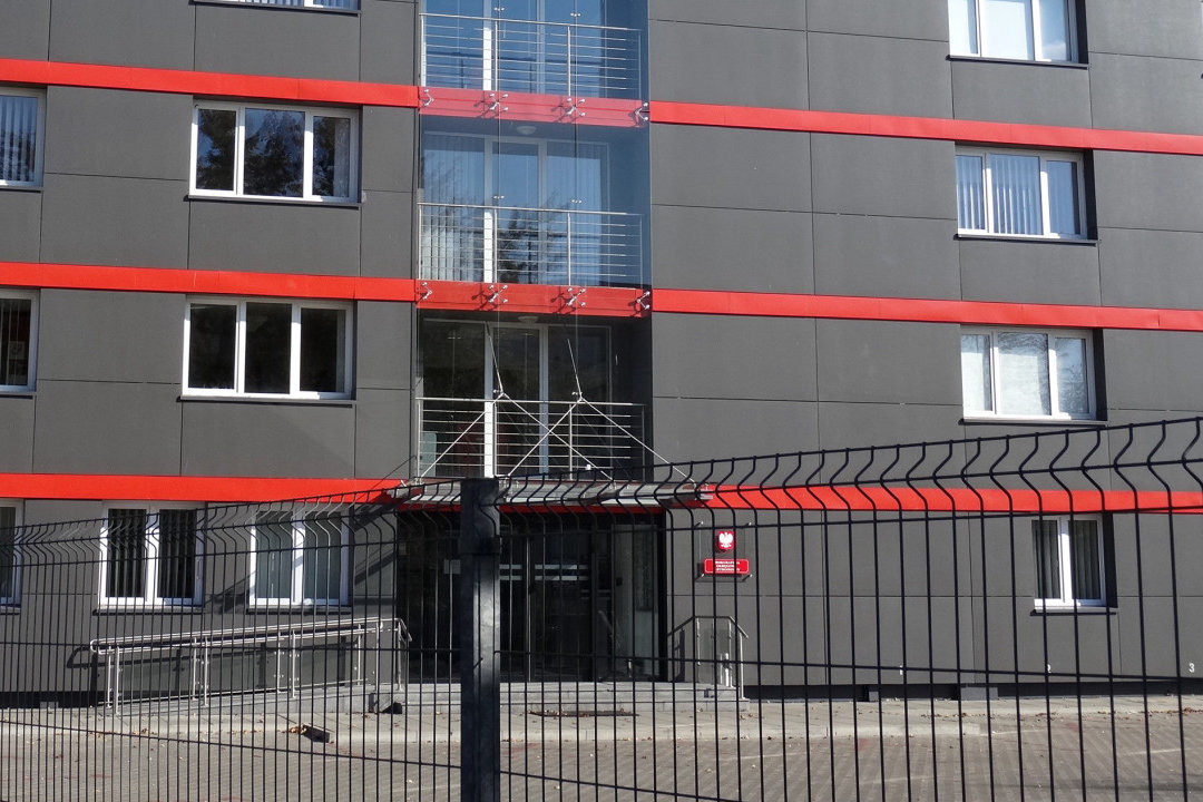 Szaro-czerwony budynek Prokuratury Okręgowej w Bydgoszczy przy ul. Okrzei, przeszklona klatka schodowa i wejście za ogrodzeniem