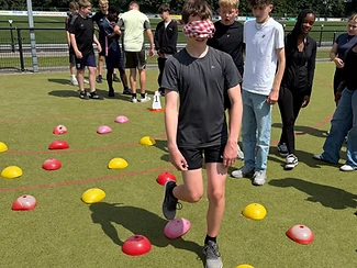 Leerling met blindfold balanceert tussen pionnen op het veld