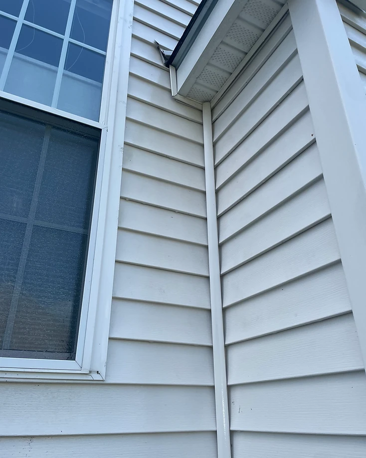 Clean vinyl siding, soffit, and window of a New England home after a soft wash