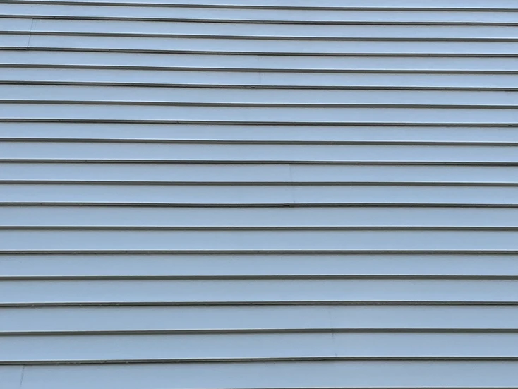 Clean white vertical vinyl siding with a wall vent after a soft wash