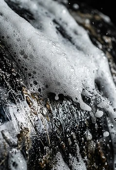 Macro of cleaning foam lifting grime from a metal surface