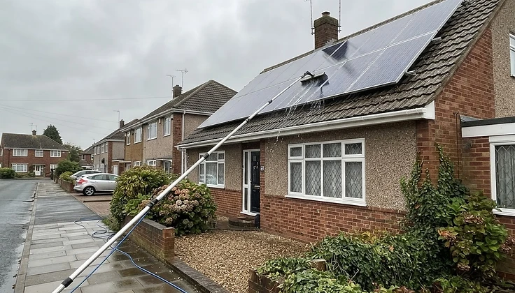 Water-fed pole brush reaching solar panels on a two storey British house from ground level