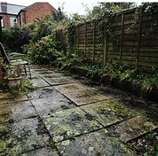 Grey concrete paving slabs covered in algae and organic build-up before cleaning
