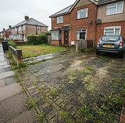 Block paving driveway covered in moss, algae and weeds in the joints before cleaning