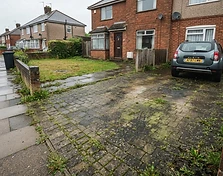 Block paving driveway covered in moss, algae and weeds in the joints before cleaning