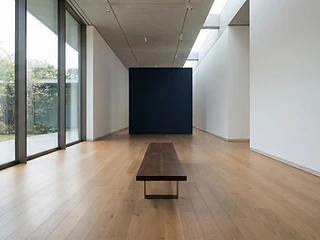 A serene modern gallery space with warm oak floors and soft natural light
