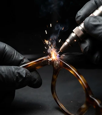 戴著黑色手術手套的技師以雷射工具修復玳瑁鏡框