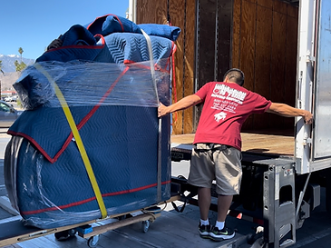 On Time Moving Services mover loading a wrapped grand piano onto a moving truck