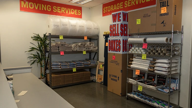 Warehouse shelving stocked with moving boxes, bubble wrap, and packing supplies