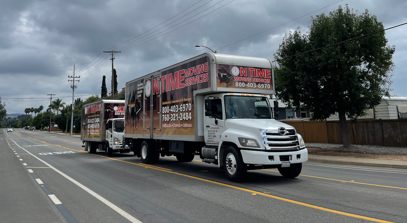 Two moving trucks parked on a paved road