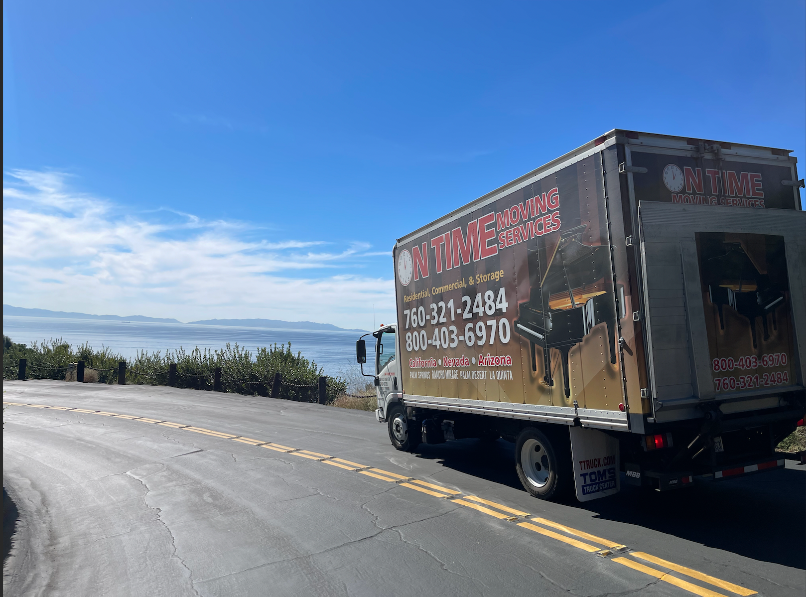 Moving truck driving on a winding road past a lake
