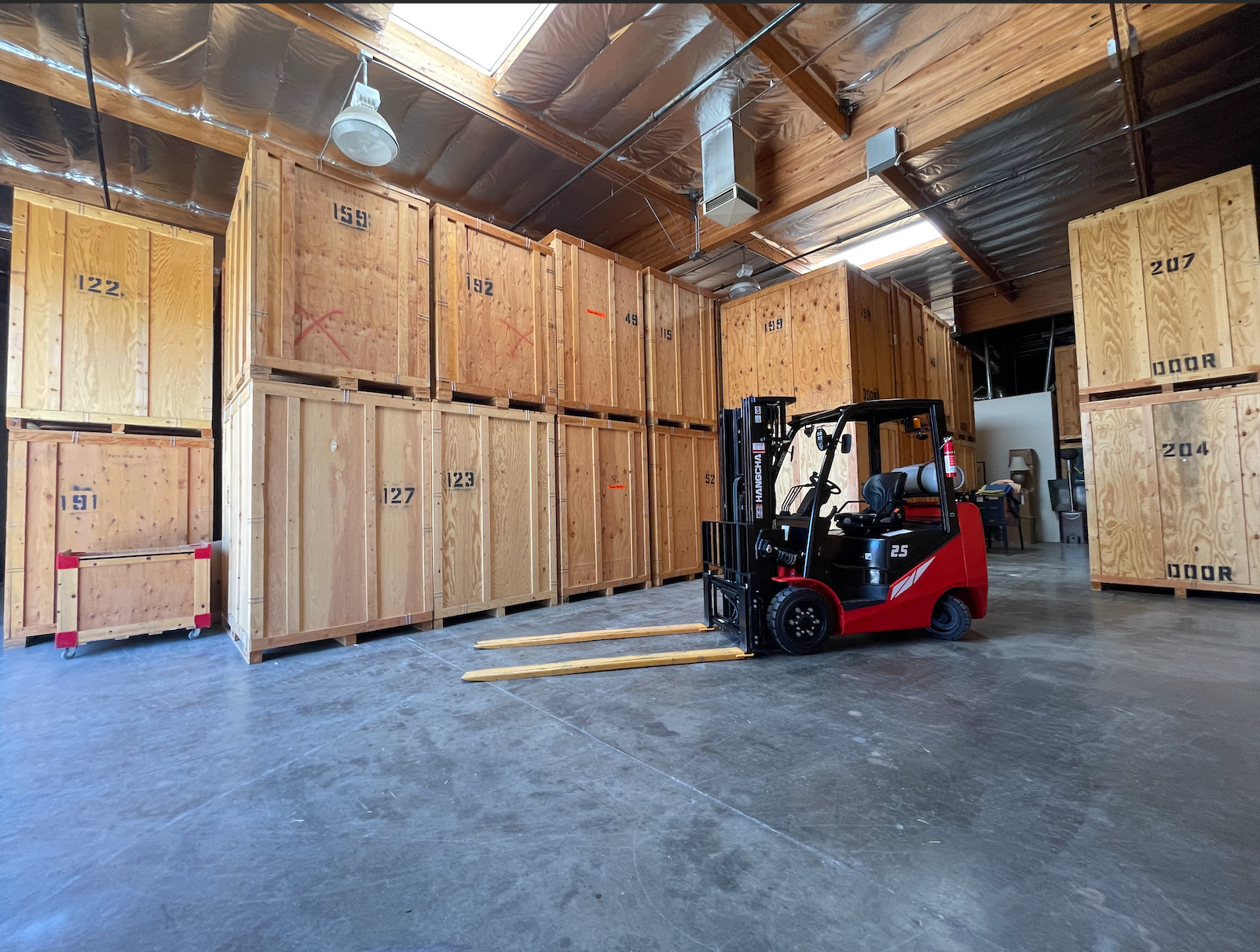 Warehouse interior with numbered wooden storage crates and a forklift