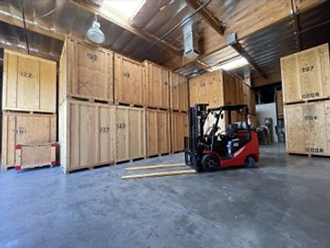 Interior of a climate-controlled storage warehouse with numbered wooden crates and a forklift