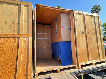 Open wooden storage pod being loaded with wrapped belongings and boxes
