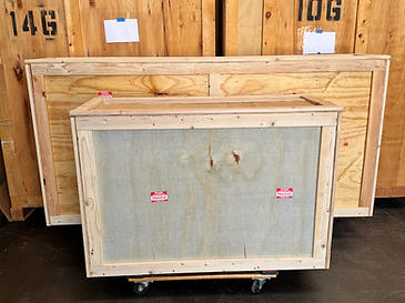 Small wooden shipping crate on a dolly in front of larger storage crates
