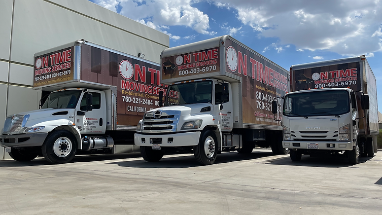 Three On Time Moving Services branded box trucks lined up in front of an industrial building