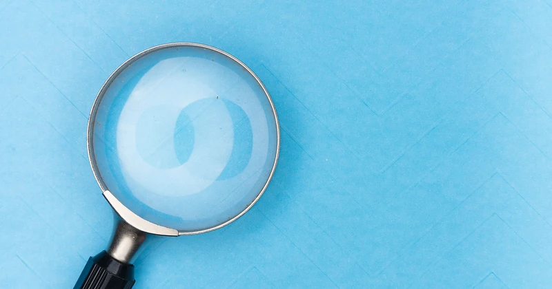 A magnifying glass over a light blue surface