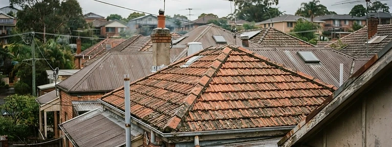 Suburban Gippsland rooftops, gutters and downpipes under overcast sky